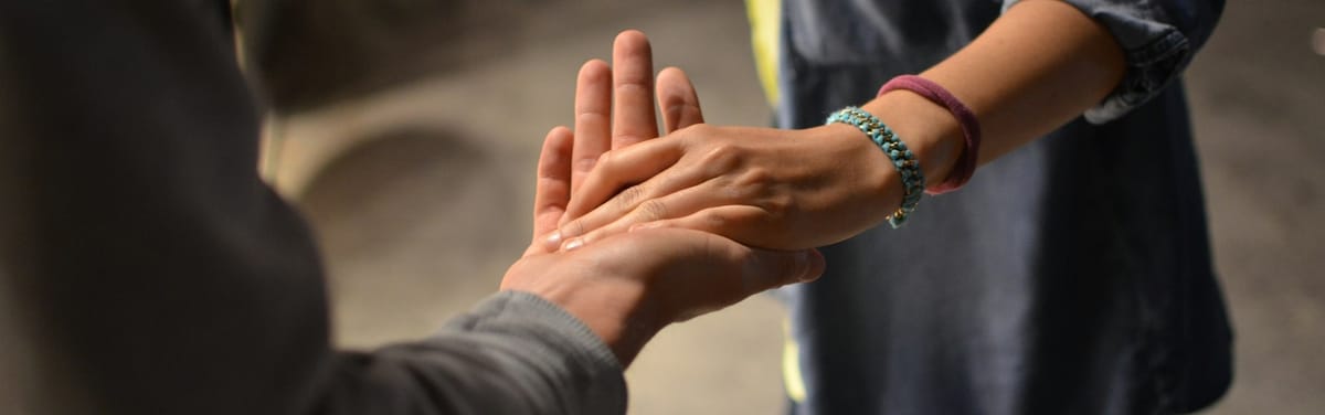 An outstretched hand being received as if to gently guide or receive the hesitant recipient