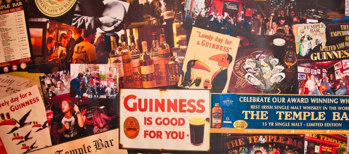 A wall covered with various Guinness and other adverts and photos likely from inside an Irish pub